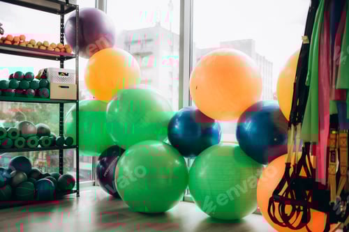 Preview: Different sports equipment and fitness balls near light wall