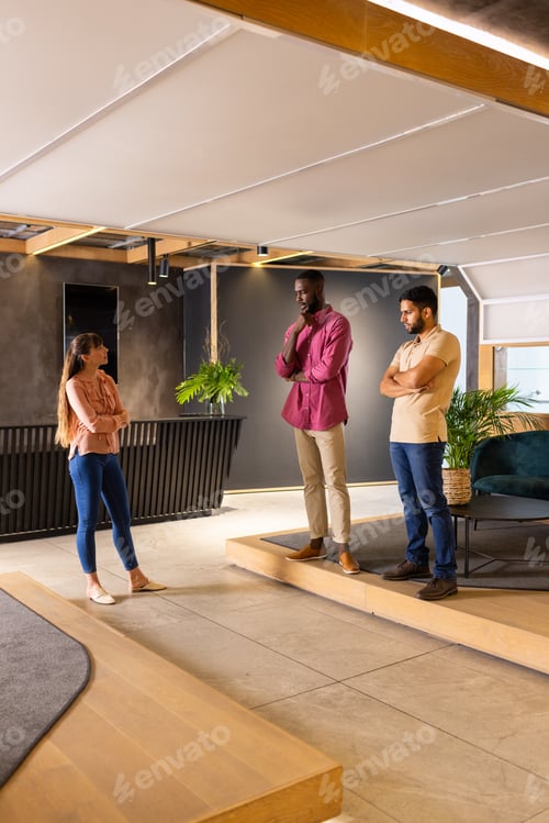 Aperçu: Discussing project ideas, three colleagues standing in modern office space