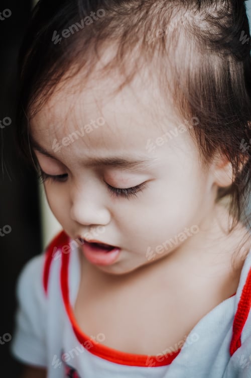 Preview: portrait of a toddler girl looking down with sad expression.