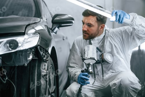 Preview: Auto Mechanic Inspecting Car Paint with Light