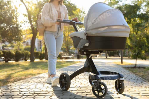 Preview: Young mother walking with her baby in stroller at park on sunny day, closeup