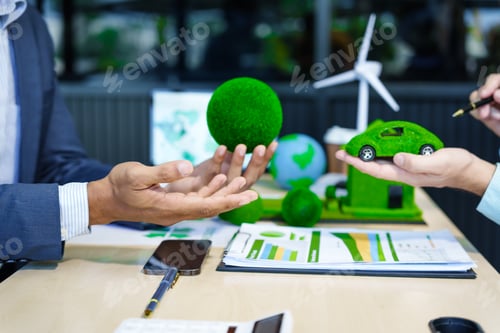 Preview: A meeting at an office desk focuses on teamwork with a house model and discussions on electric cars
