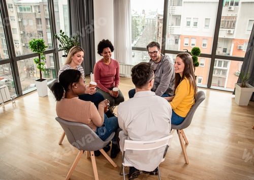 Preview: Diverse group of people sitting in circle in group therapy session.