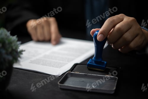 Preview: Man stamping approval of work finance banking or investment marketing documents on desk.