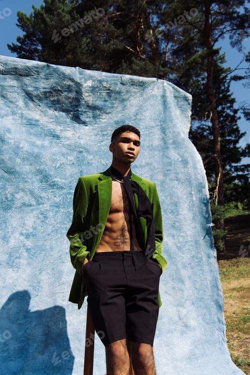 Preview: african american man in green blazer and neck scarf standing with hands in pockets near blue cloth