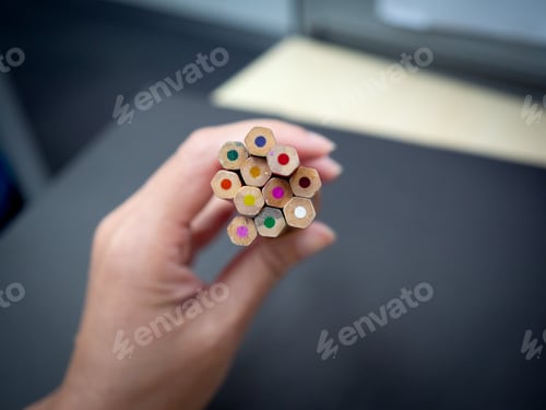 Preview: Hand holding a bunch of Multi colour pencils on black background