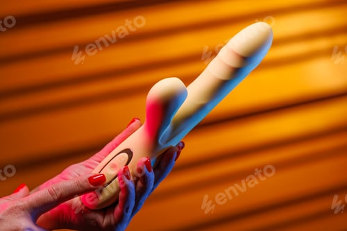 Preview: A female hand with a sensual red manicure presses the button on the vibrator.
