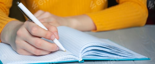 Preview: Female hand writes in a notebook. Education concept. Side view.