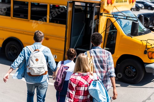 Preview: rear view of group of teen students walking to school bus after school