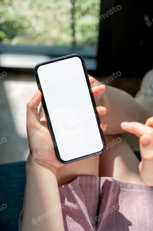Preview: female hands using smartphone at home. Blank screen mobile phone for graphic display montage.