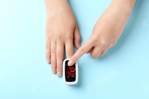 Preview: Woman using fingertip pulse oximeter on light blue background, top view