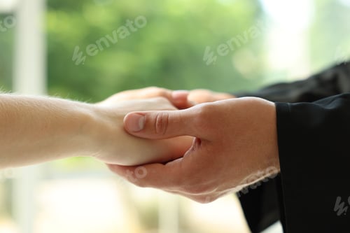 Preview: Priest and woman holding hands outdoors, closeup