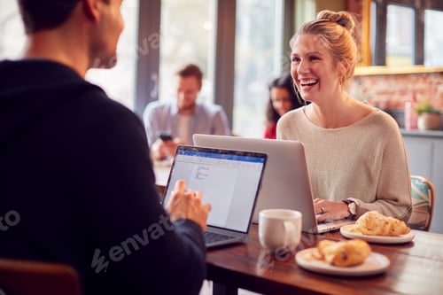 Preview: Business Couple With Laptops Having Informal Meeting In Coffee Shop