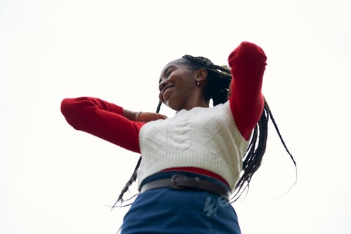 Preview: Woman in a red sweater and white vest smiling against a bright sky. Bruges, Belgium