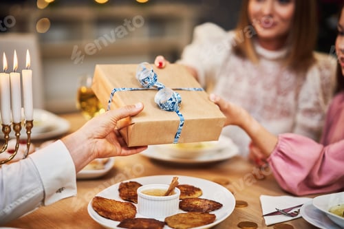 Preview: Hanukkah dinner. Family gathered around the table with traditional dishes