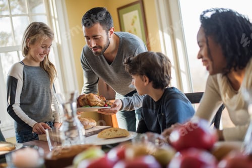 Preview: Adults and children gathered around a table for a meal.