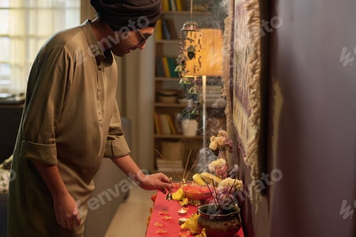 Preview: Man Preparing Religious Altar in Cozy Indoor Setting