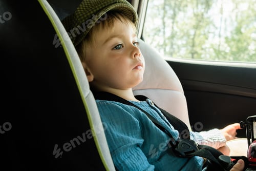 Preview: Toddler boy sitting in child safety seat in car. Car traveling with kid.