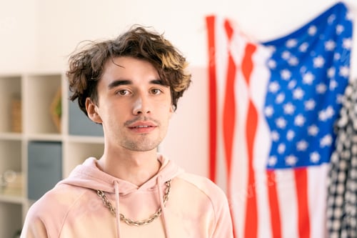 Preview: Teenage guy in pink hoodie standing in front of camera