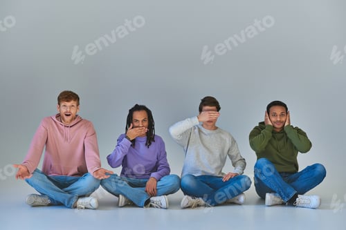 Preview: four young men sitting with crossed legs and gesturing, like four wise monkeys concept, diversity