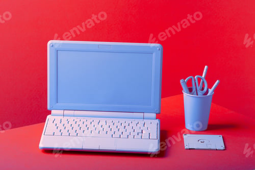 Preview: Blue laptop on a red background, with office supplies.