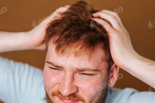 Preview: A studio shot of a guy with a head full of itchy hair, scratching his scalp in discomfort.