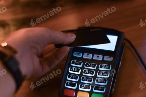 Preview: Woman’s hand using payment terminal to make debit or credit card tap payment