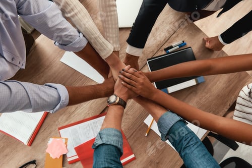 Preview: Multicultural team. Top view of business people holding hands together while sitting in the office