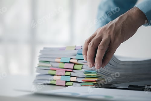 Preview: A person in an office with a huge stack of papers, he is a company employee, managing paperwork and