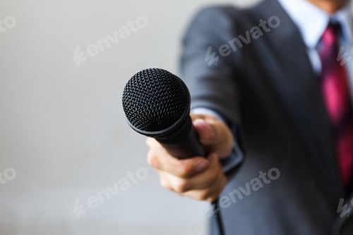 Preview: Man in business suit holding a microphone