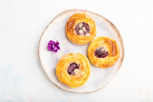 Preview: Small cheesecakes with jam and almonds with cup of coffee on a white concrete background. top view.