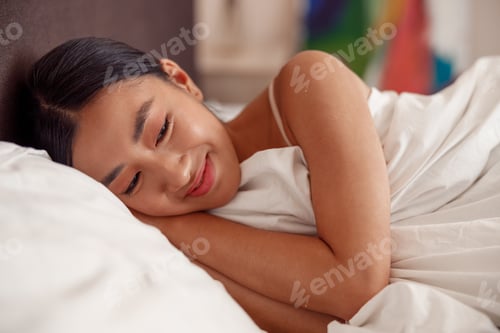 Preview: Joyful Asian woman lying in bed at home
