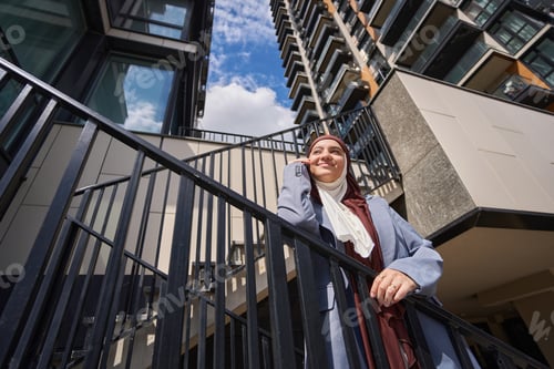 Preview: Arab woman stands on the stairs with her cheek propped on her hand