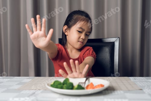 Preview: Little cute kid girl refusing to eat healthy vegetables. Children do not like to eat vegetables.