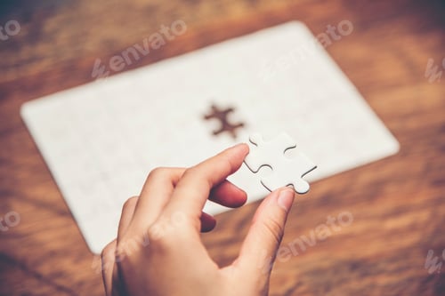 Preview: Close up of hand placing the last jigsaw puzzle piece, Hand holding missing jigsaw puzzle piece down