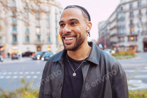 Preview: Young tourist wearing earbuds and smiling walking at city