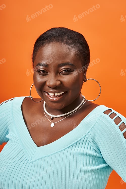 Preview: positive plus size african american woman in blue long sleeve posing on orange background