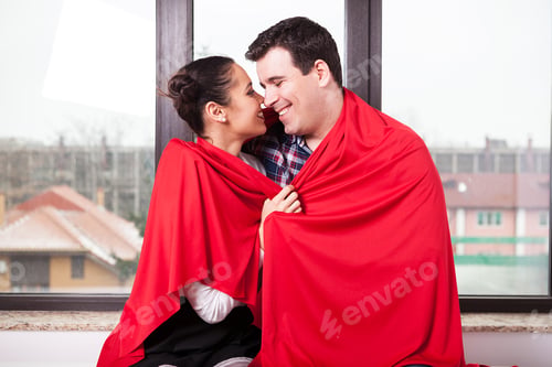 Preview: Couple covered with red blanket sitting together
