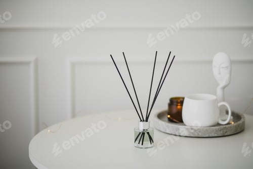 Preview: Still life with white mug, aromatic sticks and candles on a table in a cozy living room.