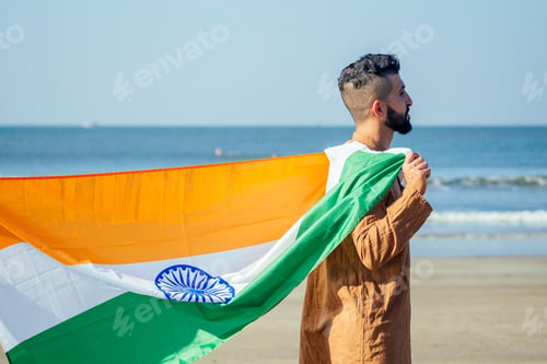 Preview: Indian young man waving indian tricolour flag outdoor near beach