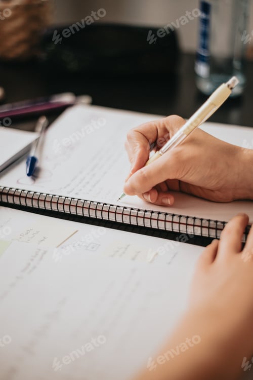 Preview: Closeup image of a woman hand writing on a notebook, doing homework during university