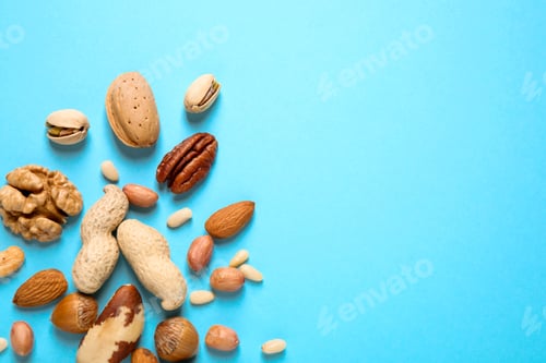 Preview: Different delicious nuts on light blue background, flat lay. Space for text