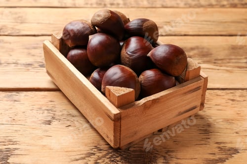 Preview: Sweet fresh edible chestnuts in crate on wooden table