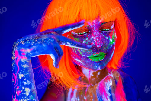 Preview: Close up UV portrait of a female model with artistic colorful makeup and orange wig