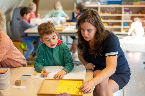 Preview: A teacher engaging with a young student during a classroom activity.