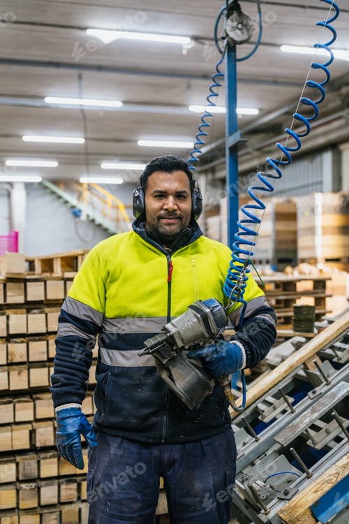 Preview: Carpenter holding nail gun assembling wooden pallets in factory