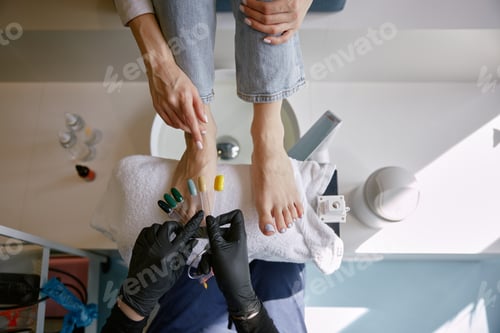Preview: View from above on client choosing color for nail during pedicure