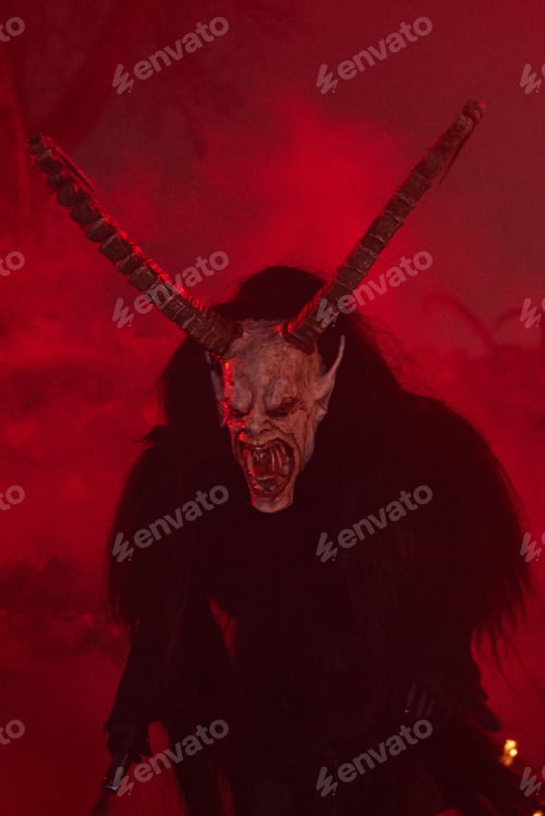 Preview: Krampus dressed in eerie face masks illuminated by a fire in the night