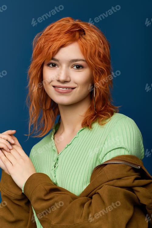 Preview: Young woman with red hair showcases vibrant spring fashion against a blue backdrop