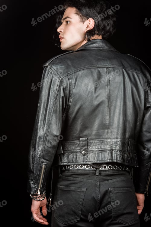 serious man in leather jacket standing isolated on black